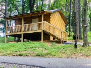a large wooden cabin with a deck in the woods at Foxtail Orchards - The Iron Horse in Tazewell