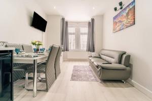 ein Wohnzimmer mit einem Tisch und einem Sofa in der Unterkunft Stylish 2Bedroom flat near train station in London in Seven Kings
