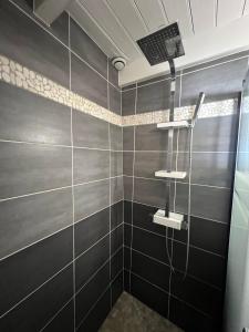 La salle de bains est pourvue d'une douche avec du carrelage noir. dans l'établissement Le Phare du Bout du Monde - Logement proche du port, à La Flotte