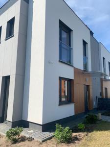 a white building with black windows at Dom „Pod lasem” w Ustce in Ustka