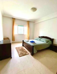 a bedroom with a bed and a window and a rug at Hayriad : Charmant 3 Chambres . Wifi, Smart TV in Rabat