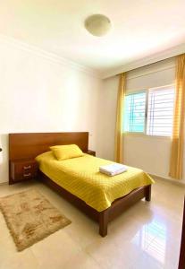1 dormitorio con 1 cama con manta amarilla y ventana en Hayriad : Charmant 3 Chambres . Wifi, Smart TV en Rabat