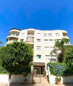 a large white building with trees in front of it at Hayriad : Charmant 3 Chambres . Wifi, Smart TV in Rabat