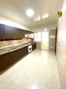 Il comprend une grande cuisine avec des placards bruns et du carrelage blanc. dans l'établissement Hayriad : Charmant 3 Chambres . Wifi, Smart TV, à Rabat