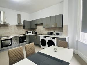 una cocina con armarios grises y una mesa con sillas. en One Battison - Affordable Rooms, Suites & Studios in Stoke on Trent en Stoke on Trent