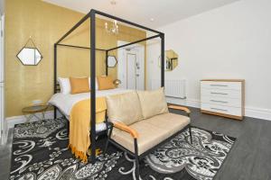 One Battison - Affordable Rooms, Suites & Studios in Stoke on Trent في ستوك أون ترينت: غرفة نوم بسرير مظلة وكرسي