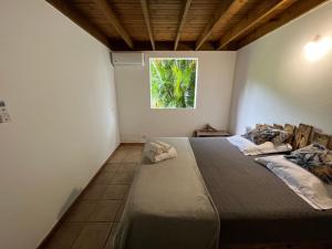 1 dormitorio con 1 cama grande y ventana en Villa Le Boursoie, villa au calme avec jacuzzis., en Les Abymes