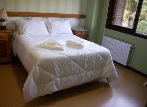 um quarto com uma cama branca com duas toalhas em Casa Felice - Canela em Canela