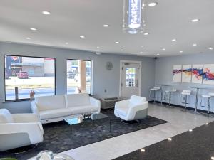 una sala de estar con sofás blancos, mesas y sillas en Deluxe Inn - Fayetteville I-95 en Fayetteville