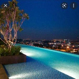 una piscina con vistas a la ciudad por la noche en i-Duplex Condo - LED Garden, Fun Fair, Wax Museum, Waterpark, Mall & More!, en Shah Alam