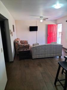 uma sala de estar com um sofá e uma porta vermelha em Adanesne Apartments em Ensenada