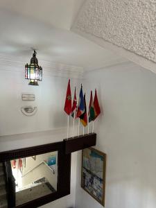 a group of flags on a wall with a chandelier at Hôtel National in Al Hoceïma