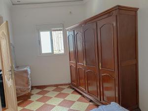 a room with a large wooden cabinet and a window at شاطئ الهدوء أمتار - استأجر كوخ محمد الربون ليوم من الاسترخاء 