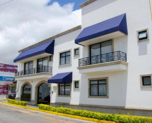 un edificio blanco con toldos azules. en Hotel Esfera Tulancingo en Tulancingo