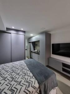 a bedroom with a bed and a flat screen tv at Flat em Boa Viagem 100% Equipado in Recife
