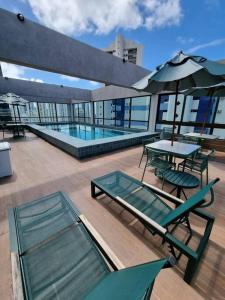 a patio with tables and chairs and a pool on a building at Flat em Boa Viagem 100% Equipado in Recife