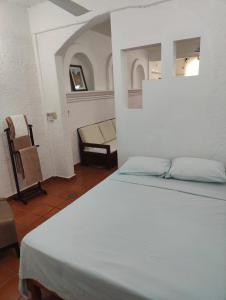1 dormitorio con 1 cama blanca y 1 silla en Villa Isabel, en Tangolunda