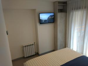 Un dormitorio con una cama y un televisor en la pared. en Monoambiente El Maiten, en San Martín de los Andes