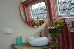a bathroom with a mirror and a vase with flowers at The IF Boutique hotel in Amsterdam