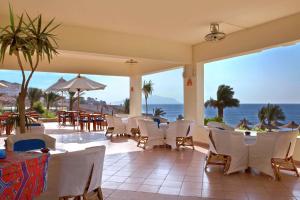 DoubleTree by Hilton Sharks Bay Resort في شرم الشيخ: مطعم به طاولات وكراسي ومطل على المحيط