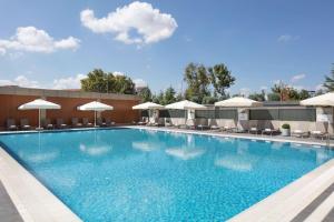 ein großer Pool mit Stühlen und Sonnenschirmen in der Unterkunft Hilton Istanbul Bakirkoy in Istanbul