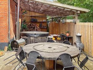 a patio with a wooden table and chairs and a grill at Holiday home Grindsted IV in Grindsted