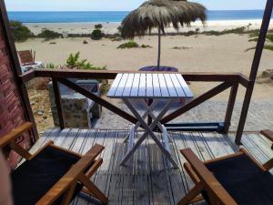 Cabañas Paraiso في باهيا انغليسا: سطح خشبي مع طاولة وكراسي على الشاطئ