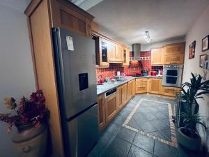 La cuisine est équipée d'armoires en bois et d'un réfrigérateur en acier inoxydable. dans l'établissement Fernway Residence entire property, à Cork