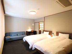 1 dormitorio con 2 camas y sofá azul en RONENAI BASE, en Biei