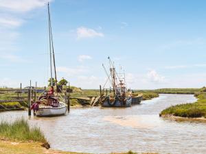 two boats are docked in a river at Mcauley Cottage in Burgh le Marsh