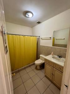 La salle de bains est pourvue d'un rideau de douche jaune et de toilettes. dans l'établissement SAM TRAVEL, à Managua