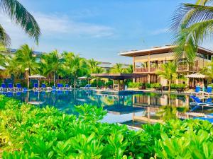 a resort swimming pool with blue chairs and palm trees at Sonaga Beach Resort & Villas Phu Quoc in Phú Quốc