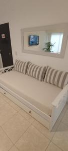 eine weiße Couch mit gestreiften Kissen in einem Zimmer in der Unterkunft ALOJAMIENTO LA ESTACIÓN in Gualeguaychú