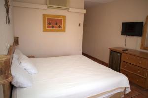 a bedroom with a white bed and a television at La Concha Beach Hotel & Club in La Paz