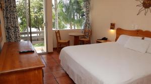 a bedroom with a bed and a desk and a window at La Concha Beach Hotel & Club in La Paz