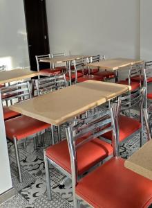 an empty classroom with desks and red chairs at Hotel Guadalupe Acacías in Acacías