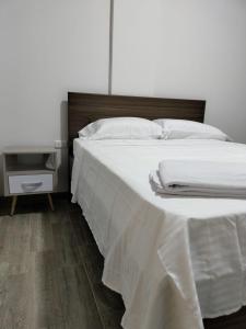 een bed met witte lakens en een houten hoofdeinde bij Hotel Guadalupe Acacías in Acacías