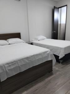 two beds sitting next to each other in a bedroom at Hotel Guadalupe Acacías in Acacías