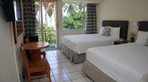 a hotel room with two beds and a table and a window at La Concha Beach Hotel & Club in La Paz