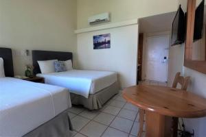 a hotel room with two beds and a table at La Concha Beach Hotel & Club in La Paz