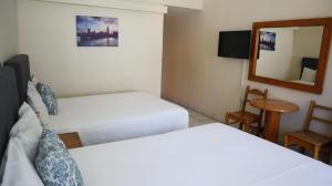 a hotel room with two beds and a mirror at La Concha Beach Hotel & Club in La Paz