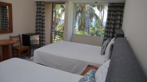 a bedroom with two beds and a window with palm trees at La Concha Beach Hotel & Club in La Paz