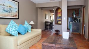 a living room with a couch with blue pillows on it at La Concha Beach Hotel & Club in La Paz