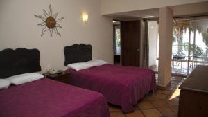 two beds in a room with purple blankets at La Concha Beach Hotel & Club in La Paz