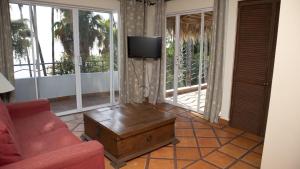 a living room with a couch and a tv and a table at La Concha Beach Hotel & Club in La Paz