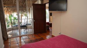 a room with a bed and a balcony with a television at La Concha Beach Hotel & Club in La Paz