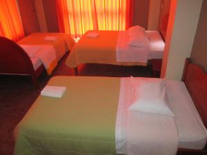 a hotel room with three beds and a table at Hotel Villa Santa Ana in Quillabamba