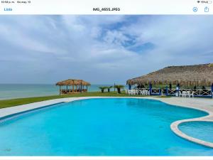 a resort swimming pool with a view of the ocean at Villa Nilsa ( The Blue House ) in Baní