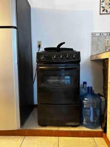 einen schwarzen Herd in einer Küche neben einem Kühlschrank in der Unterkunft Amplia Casa/Residencia a 15 Minutos de playa Miramar y Altama in Tampico