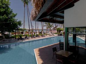 a swimming pool with chairs and a table next to a building at La Concha Beach Hotel & Club in La Paz